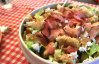 Salade deluxe met krokante kip, bacon, avocado, boursin en appel-knoflook dressing 